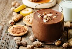 a chocolate smoothie with nuts and milk on a table next to other food items