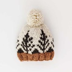 a brown and white knitted hat with pom - pom