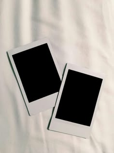 two polaroid frames sitting on top of a white sheet