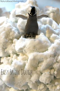 a close up of a small toy penguin on top of cauliflower with the words easy snow dough written below it