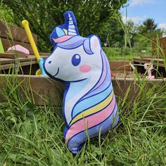 a stuffed toy unicorn sitting in the grass