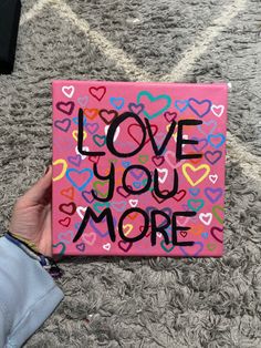 someone is holding up a pink box with hearts on it that says love you more