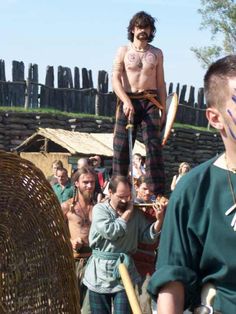 two men are standing on stilts in front of a group of people with painted faces