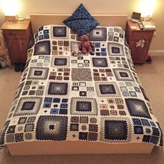 there is a bed with a quilt on it and a teddy bear in the middle