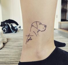 a small tattoo on the ankle of a woman's leg with a dog head