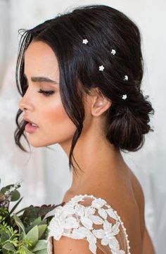 a woman with flowers in her hair wearing a wedding dress and holding a flower bouquet