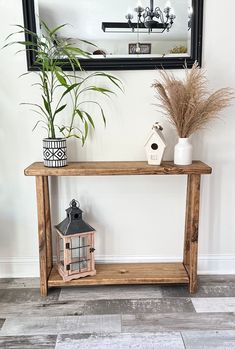 a wooden table sitting next to a mirror on top of a wall with a potted plant