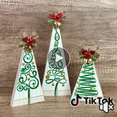 three wooden christmas trees with bows and ribbons on them, one is green and the other is white