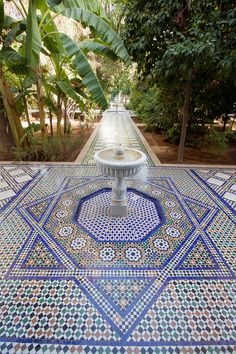 a fountain in the middle of a garden with blue and green tilework on it