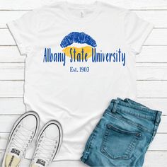 Albany State University Golden Rams T-SHIRT. Be fly and rep your college and school colors in this custom piece. Great unisex design that's flattering for both men and women. This T-shirt fits most customers true to size. It is a soft, relaxed fit. Available T-shirt colors: White, Black, Gray - 100% combed and ring-spun cotton (Bella Canvas 3001) - Fabric weight: 4.2 oz/y² (142 g/m²) - Pre-shrunk fabric - Shoulder-to-shoulder taping - Side-seamed - Retail fit (more tailored with fitted sleeves) College Style T-shirt With Letter Print, White Crew Neck T-shirt For College Events, College Style Crew Neck T-shirt With Team Name, Fan Apparel T-shirt With Team Name For College Events, Sporty Short Sleeve T-shirt For College Events, Cotton Fan Apparel T-shirt For College Events, White Tops For College Events, Casual White Tops For College Events, Crew Neck T-shirt For College Events With Fan Apparel