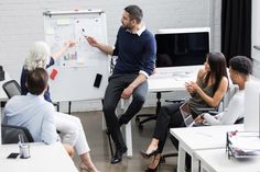 a group of people sitting around a white board