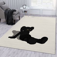 a black teddy bear sitting on top of a rug in a living room next to a chair