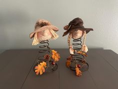 two scarecrows with hats on top of each other sitting on a wooden table