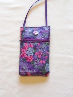 a purple flowered purse is on a white sheet