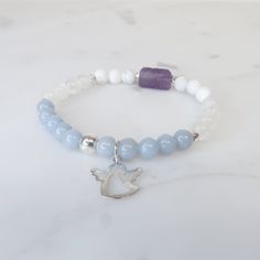 This bracelet was made to help you connect with your angels and guides and to remind you that they are always by your side. Crafted with AAA Grade 6mm Angelite, Selenite, Howlite, Amethyst, Hematite and accessorized with a silver Angel Charm to facilitate the connection between you and your Angels & Guides. Stone Details Angelite enhances communication with Angels and higher beings of light. It helps to amplify your telepathic connection with angels as it works to send out and receive messages. White Spiritual Charm Bracelet For Friendship, White Amethyst Beaded Bracelet As Gift, White Amethyst Beaded Bracelets As Gift, Spiritual Healing Crystal Bracelet With Birthstone, White Amethyst Beaded Bracelets For Spiritual Style, White Amethyst Bracelet With Natural Stones, White Amethyst Gemstone Beaded Bracelets, White Amethyst Beaded Gemstone Bracelets, White Amethyst Jewelry With 8mm Beads