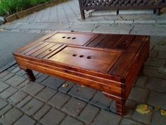 a wooden table sitting on the side of a road next to a bench with holes in it