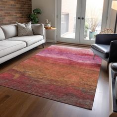 a living room filled with furniture and a rug on top of a hard wood floor