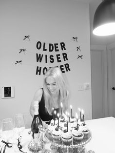 a woman is blowing out candles on cupcakes