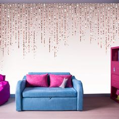 a blue couch sitting in front of a wall with pink and purple decorations on it