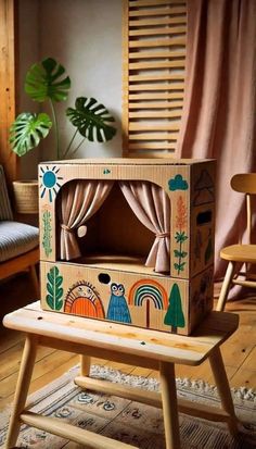 a wooden toy house sitting on top of a wooden bench in front of a window