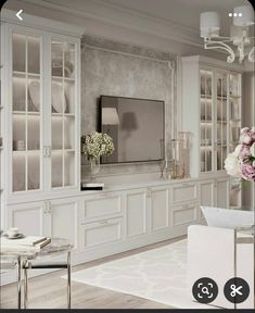 a living room with white furniture and flowers in vases on the wall next to it