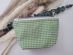 The bag is a green checkered bag with a light flower pattern inside. It has a silver zipper with lace on both ends. It is hand made and durable. Green Cosmetic Bag With Removable Pouch For Everyday, Green Pouch Cosmetic Bag For Everyday Use, Everyday Green Zipper Pouch Cosmetic Bag, Green Pouch Coin Purse For Everyday, Green Coin Purse With Zipper As Gift, Green School Bag With Zipper Pouch, Green Cosmetic Bag Pouch For Personal Use, Green School Pouch, Green Rectangular Cosmetic Bag For School