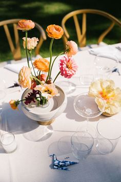 an arrangement of flowers and wine glasses on a table