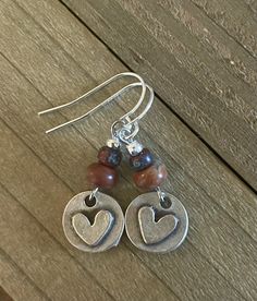 These dainty silver heart earrings are adorable!  They have pretty jasper gemstones and garnet colored Picasso beads.  The antiqued silver plated hearts look great with the jasper beads.  These cute earrings are a little  over 1 inche in length.   ~I use high quality hypoallergenic materials along with many different colors and types of beads.  I work hard to create beautiful pieces and to provide excellent customer service.   Packaging All of my earrings come packaged in a pretty drawstring bag Silver Heart Earrings, Jewelry Minimalist, Disc Earrings, I Work Hard, Boho Gifts, Jasper Beads, Antique Earrings, Gift Jewelry, Metal Earrings