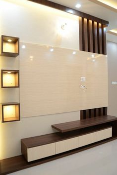 a modern living room with white walls and wooden shelves on the wall, along with recessed lighting