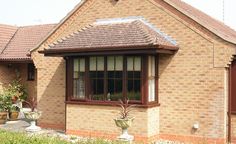 a brick house with potted plants in the front yard and windows on each side