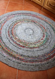 a round rug made out of magazines on the floor in a kitchen with wooden cabinets