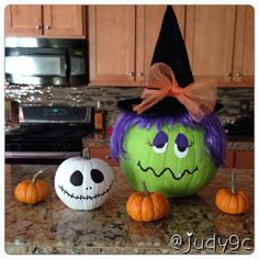 two pumpkins with faces painted on them sitting on a kitchen counter