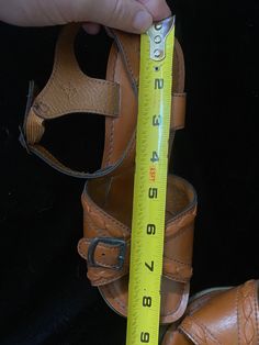 Very funky 1950's brown leather sandals with wooden cut out wedge heels. Bottoms are a soft black material, one shoe is missing a chunk of the soft bottom by the heel, shown in photo. I have not repaired. Wood heels have some scratches. Being sold as is Women's size 5 Vintage Closed Toe Sandals With Leather Footbed, Vintage Leather Sandals With Round Toe, Vintage Leather Sandals For Beach, Vintage Leather Sandals For The Beach, Vintage Leather Huarache Sandals For Summer, Retro Leather Sandals With Stacked Heel, Retro Sandals With Leather Sole, Retro Leather Sandals With Heel Loop, Vintage Leather Huarache Sandals For Beach