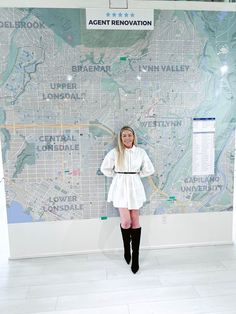 a woman standing in front of a map with her hands on her hips and legs crossed