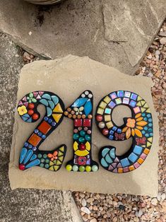 a stone with the number twenty nine made out of colorful glass and pebbles on it