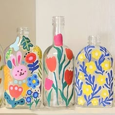 three glass bottles with painted designs on them