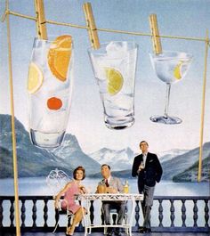 three people sitting at a table in front of two glasses with lemons on them