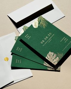 four green and white envelopes with gold foil designs on them, sitting next to each other