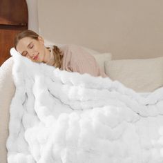 a woman laying on top of a couch under a white blanket