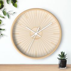 a clock on the wall next to a potted plant and a vase with green leaves