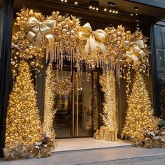 an entrance to a store decorated with gold and white christmas trees, bows and ornaments