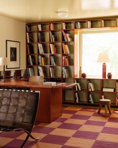 a room with bookshelves, desk and chair in front of a large window