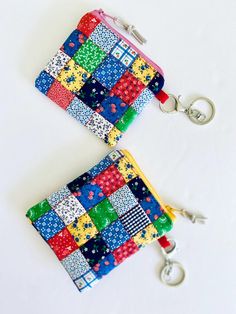 two multicolored patchwork purses with keychains on white table top