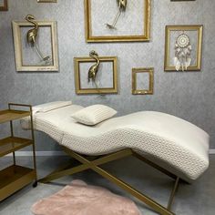 a white chaise lounge chair sitting in front of pictures on the wall