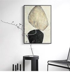 a black and white painting hanging on the wall next to a chair with a plant in it