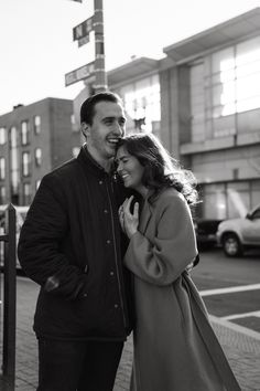 a man and woman standing next to each other on a sidewalk in front of a building