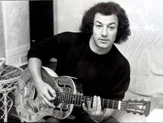 a black and white photo of a man playing an acoustic guitar