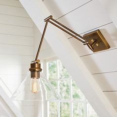 a light that is hanging from the ceiling in a room with white walls and beams