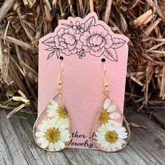 a pair of earrings with flowers on them sitting in front of a pink card that says, mother's day jewelry