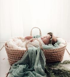 a baby is laying in a basket with a blanket on the floor next to it